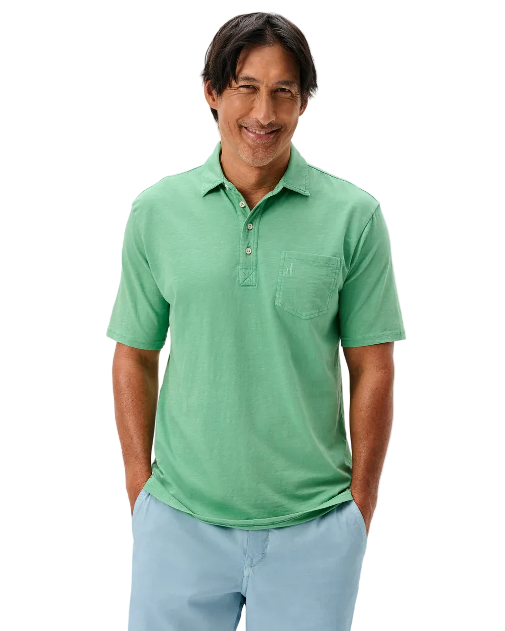 Man wearing a green polo shirt and light blue pants on a plain background