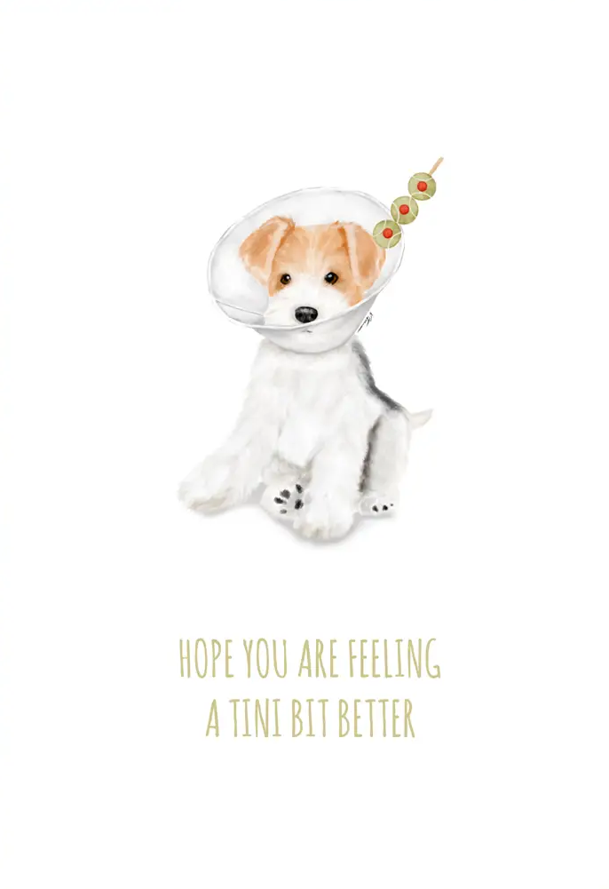 A white greeting card with a watercolor illustration of a small white dog wearing a clear face mask and gold beads, with the text 'HOPE YOU ARE FEELING A TINI BIT BETTER' in gold below. The card is shown with a brown kraft envelope behind it on a light neutral background.