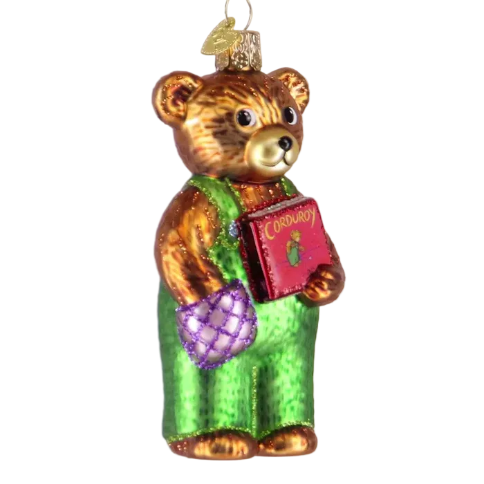 Glass bear ornament holding a book and purple egg on a light beige background