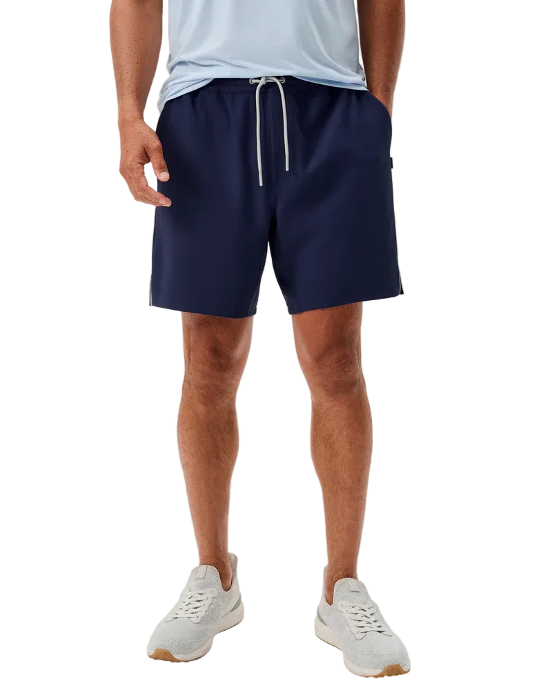 Person wearing navy shorts and light blue shirt on a white background