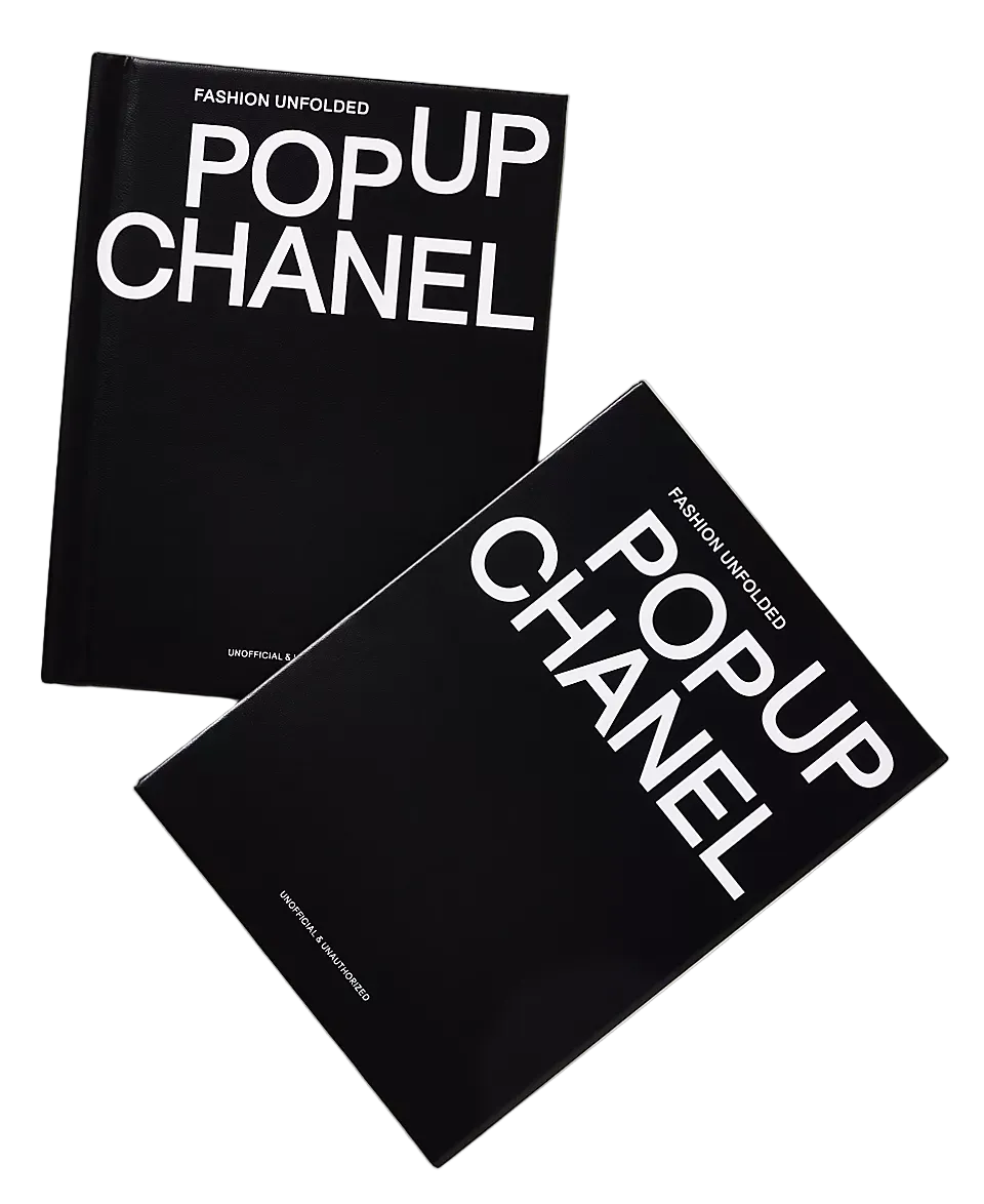 Two black hardcover books titled 'POPUP CHANEL' with large white text, arranged overlapping on a light neutral background.