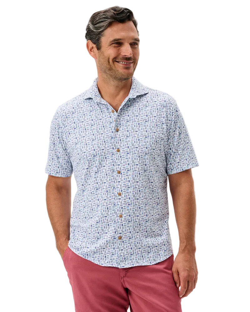 Man wearing a patterned short-sleeve shirt and red pants on a light gray background