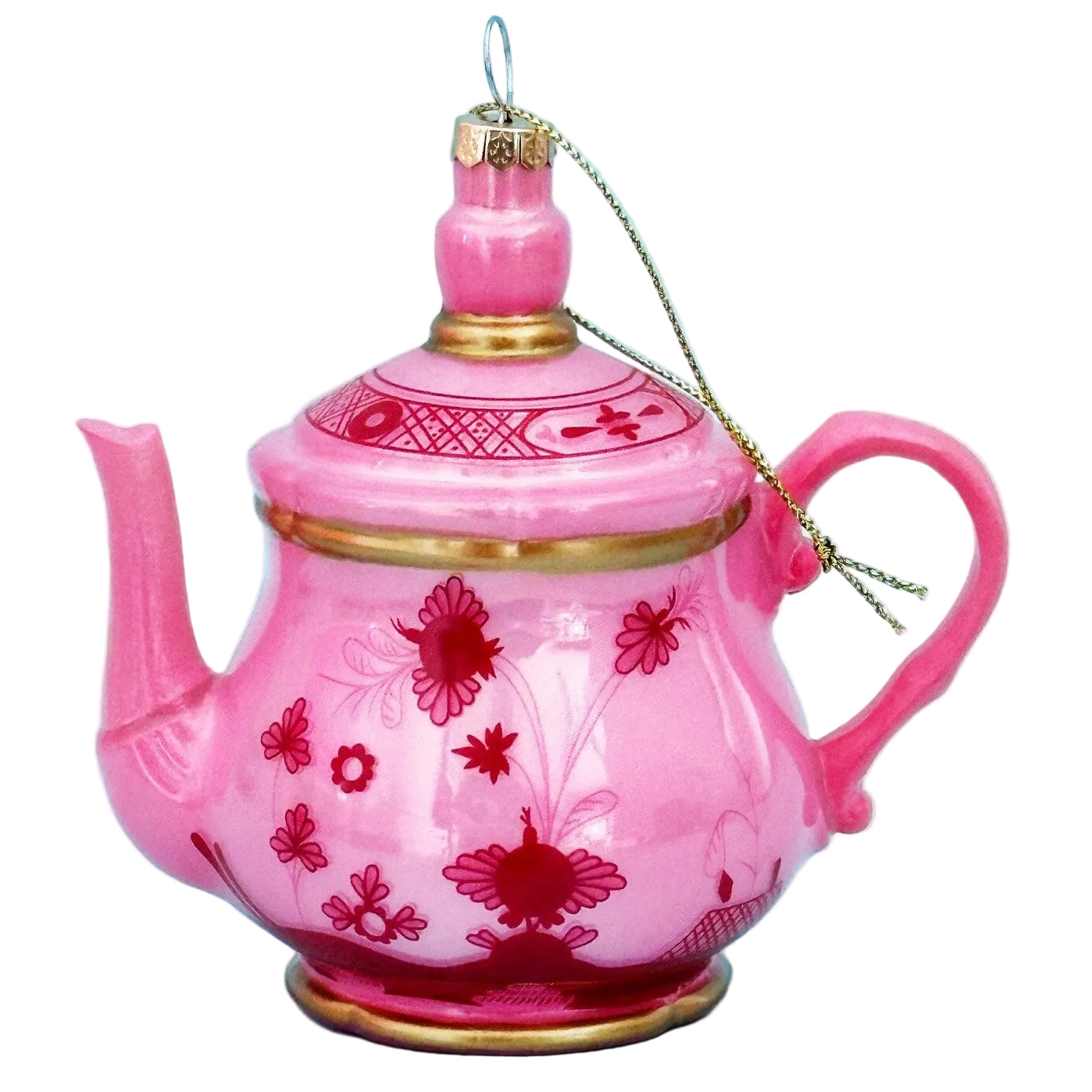 A pink ceramic ornament shaped like a teapot, decorated with red floral patterns and gold trim, hanging against a light blue background.