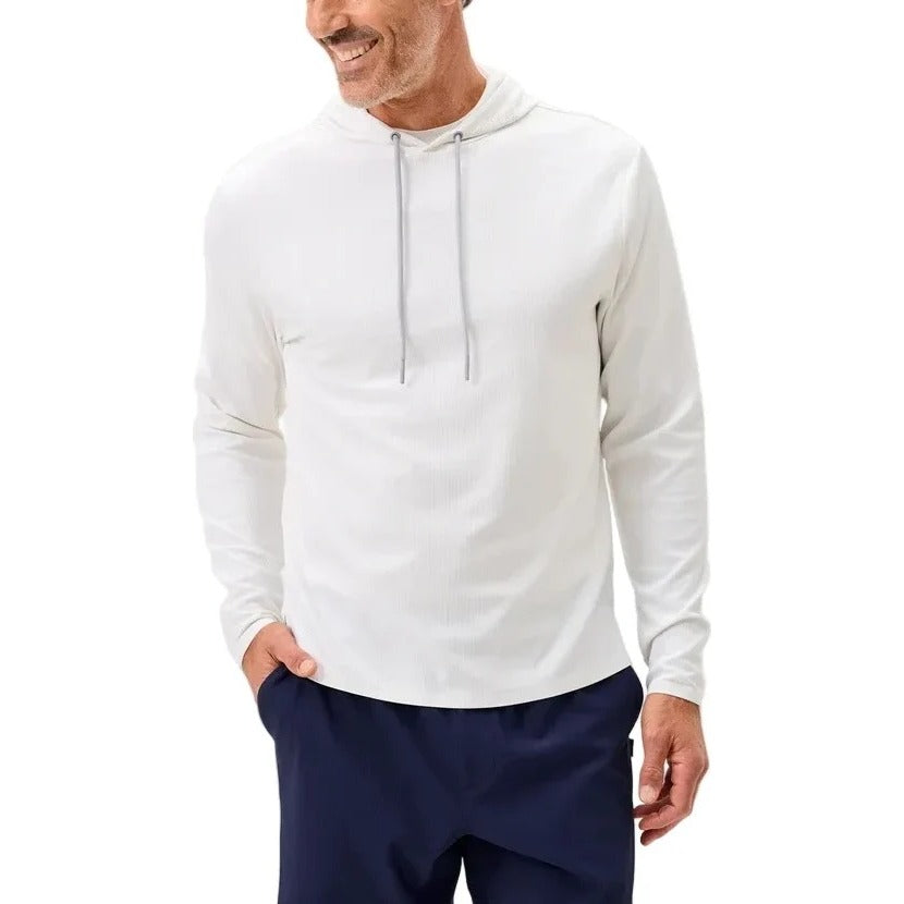 Man wearing a white hoodie and navy pants on a light gray background