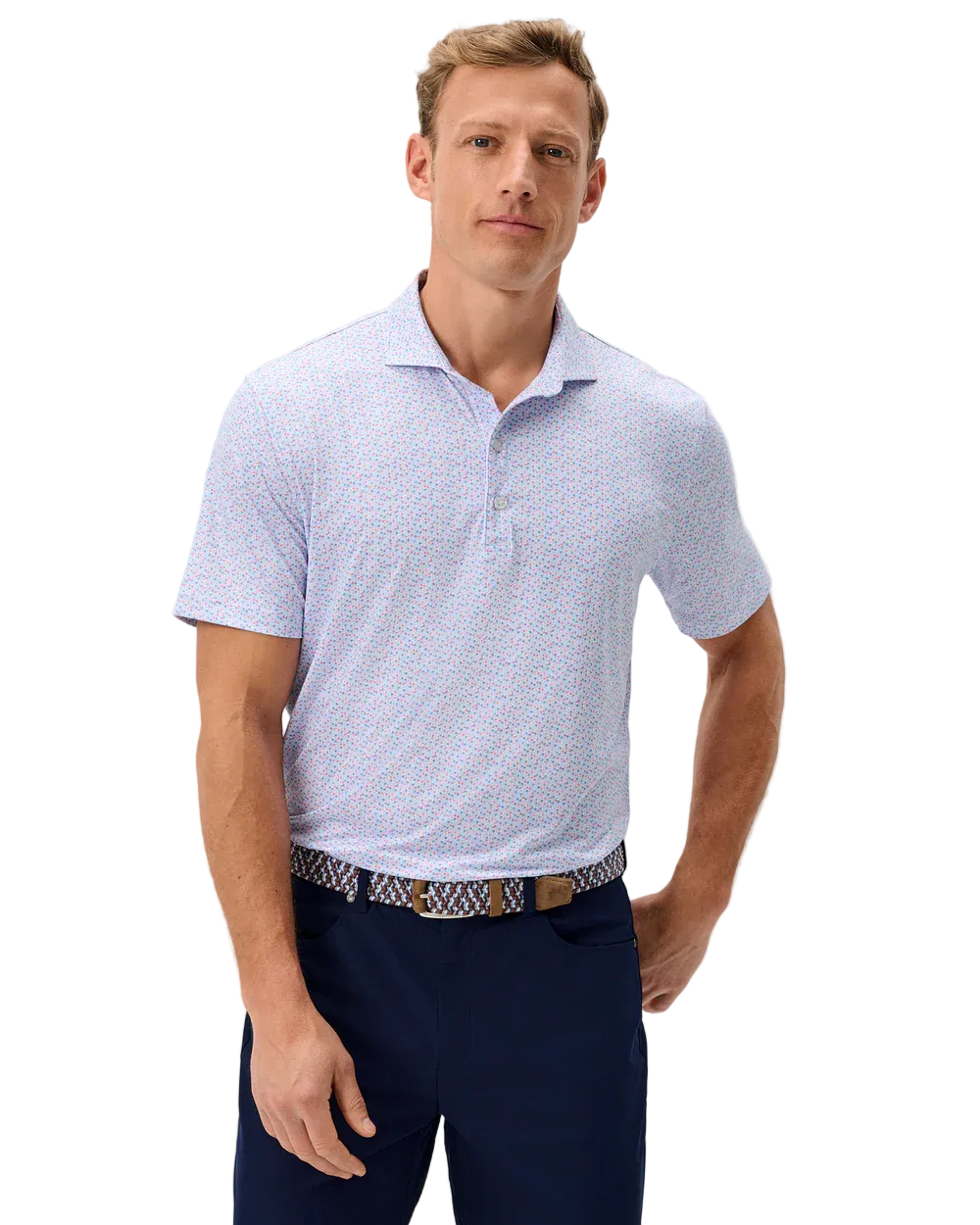 Man wearing a light blue patterned polo shirt and navy pants on a gray background