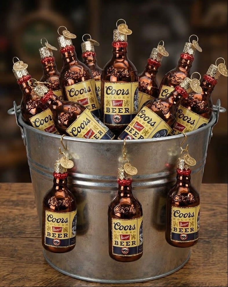 Metal bucket filled with Coors beer bottles and labels on a wooden surface.