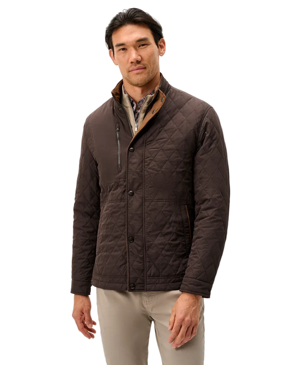 A man wearing a dark brown diamond-quilted jacket with a tan-lined collar over a patterned shirt and beige trousers, standing against a light gray studio background.