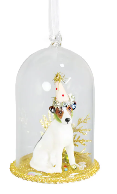 A clear glass cloche hanging ornament featuring a small white dog figurine wearing a gold party hat and surrounded by gold leaf details, set against a plain white background.