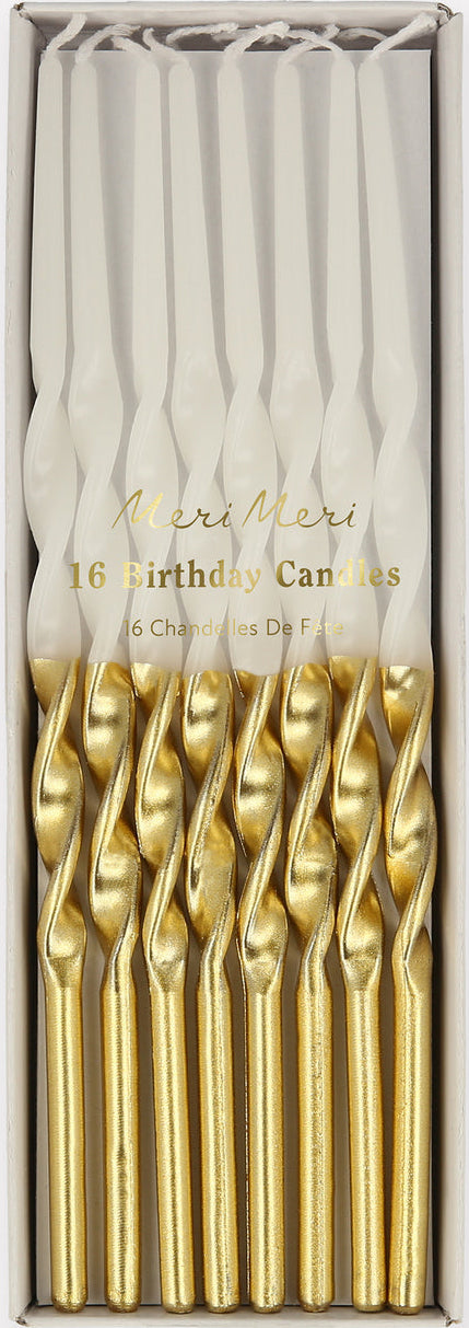 A boxed set of 16 birthday candles with white wax and metallic gold twisted handles, presented in a clear-fronted rectangular package on a light gray background.