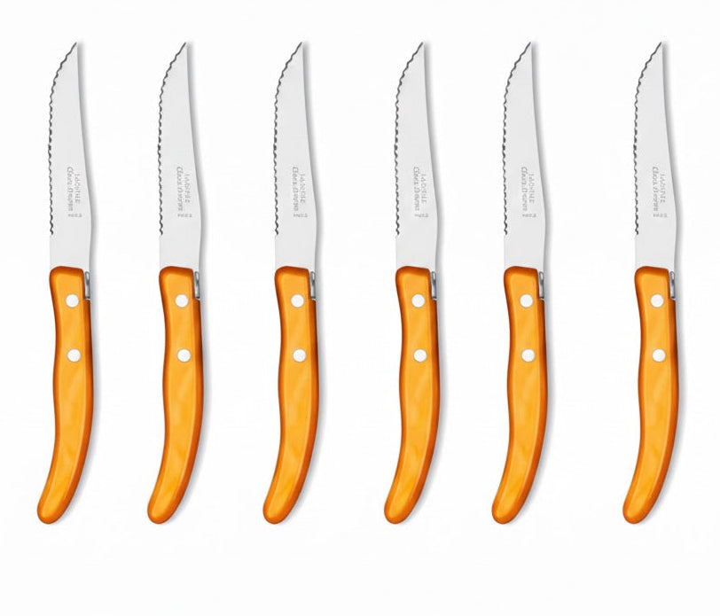 Set of six steak knives with orange handles on a white background